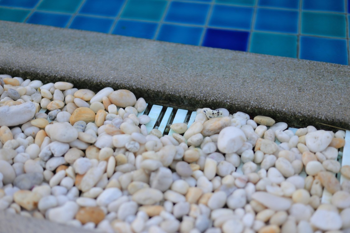 pool deck drain hidden with rocks